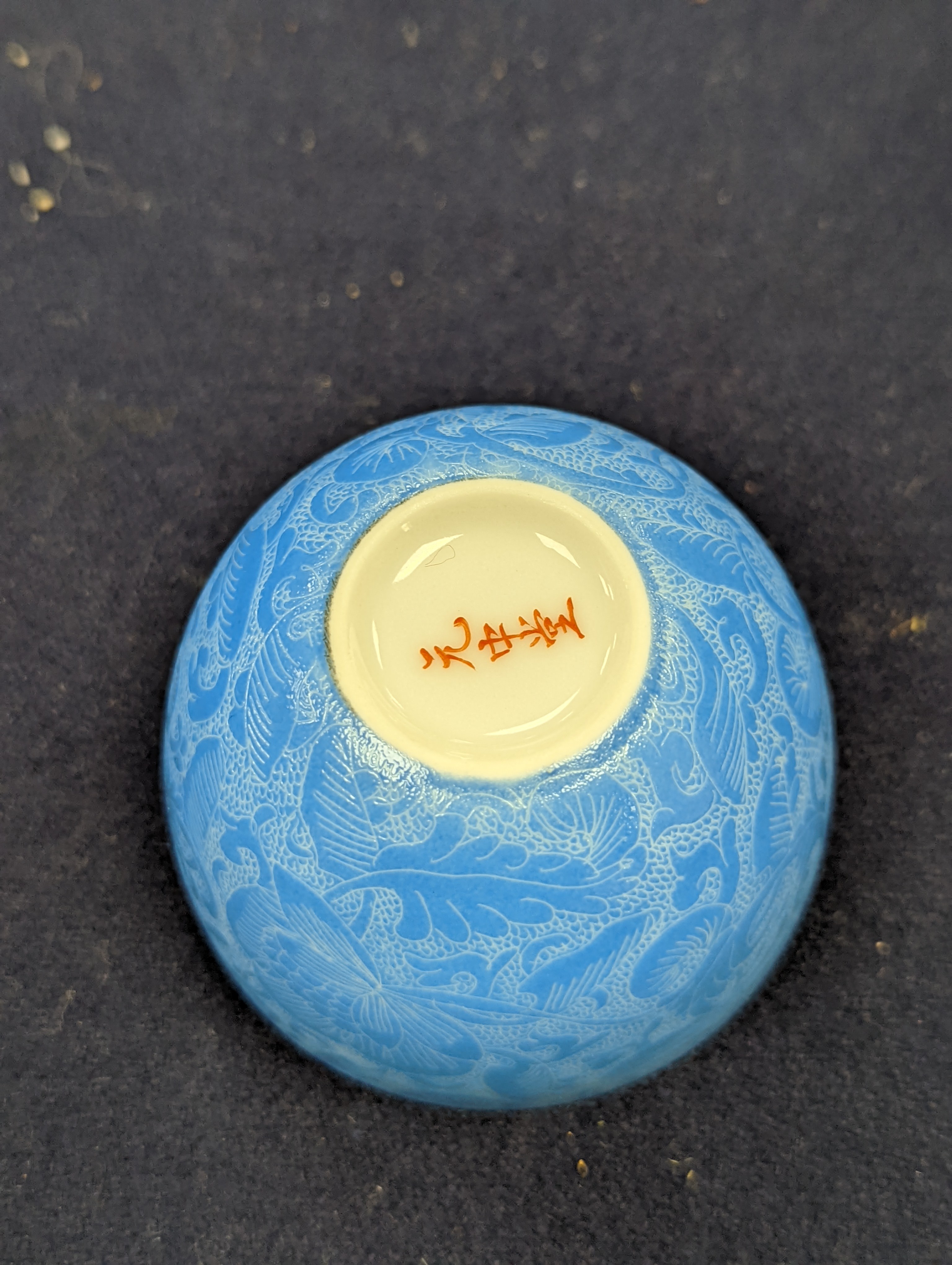 A Japanese or Chinese sgrafitto blue enamelled cup, cased. 6cm diameter